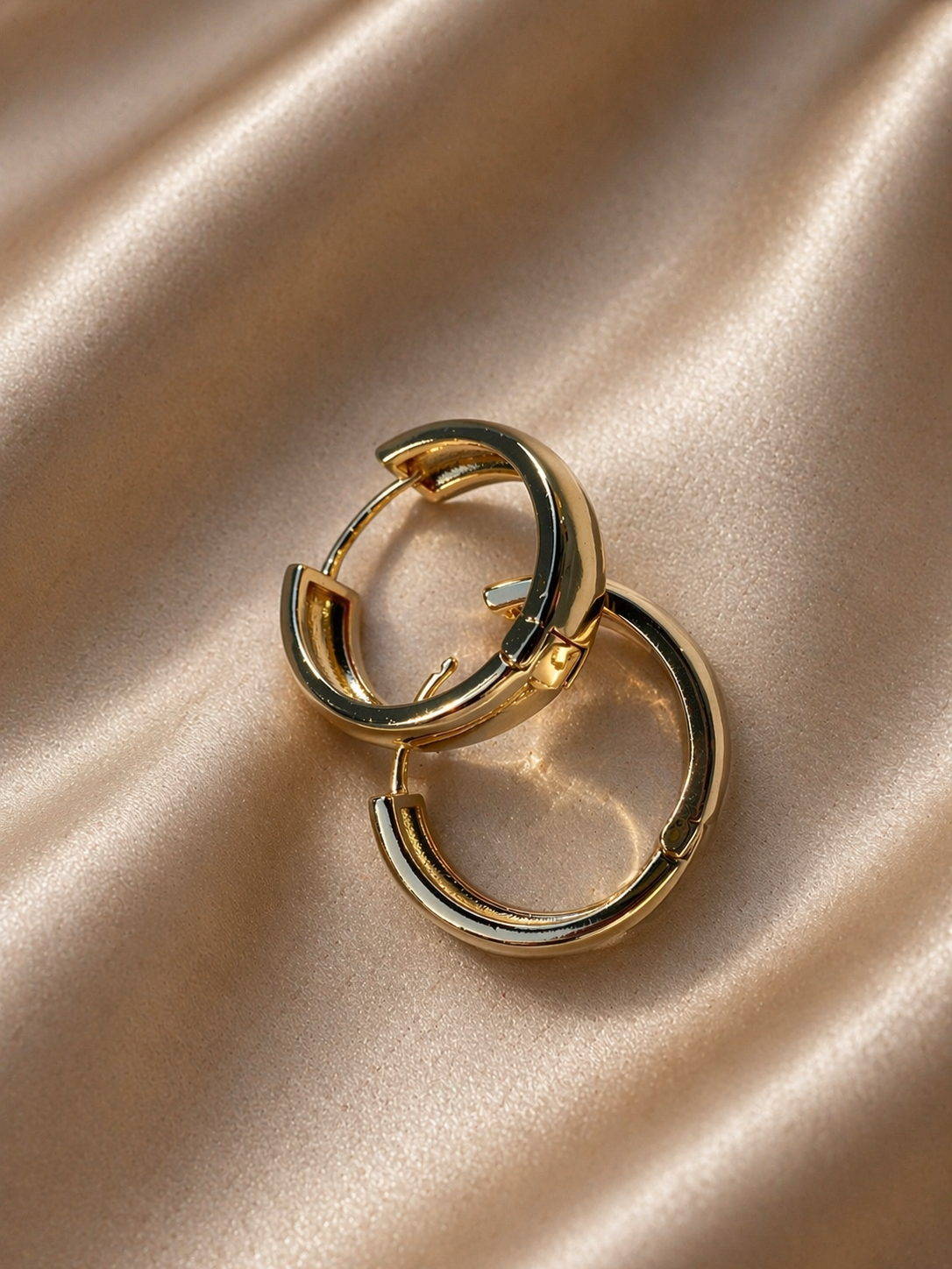 Gold hoop earrings on a beige fabric background