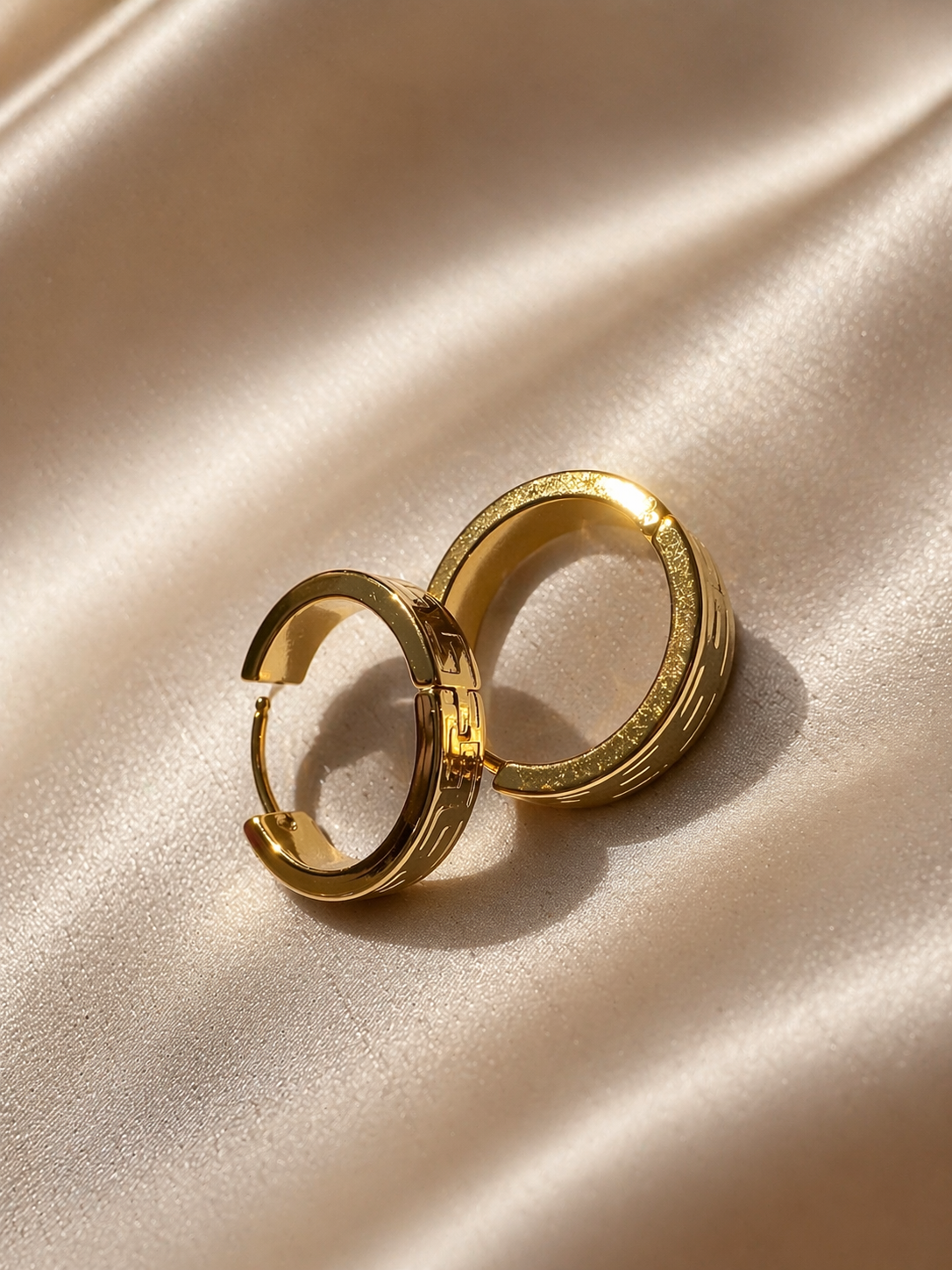 Gold hoop earrings on a beige satin surface